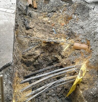 Ein aufgegrabener Straßenabschnitt, im Untergrund befnden sich eine Reihe von Kabeln.