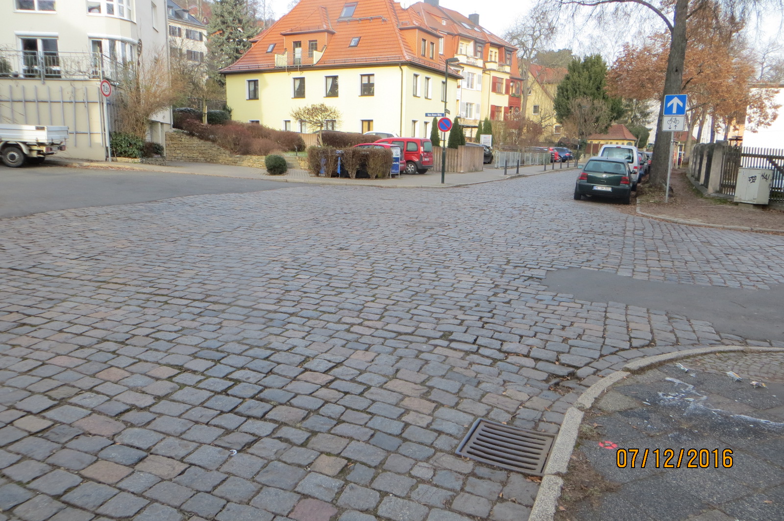 Blick in die Thomas-Mann-Straße, Kreuzung. Die Straße ist geplastert, rechts parken Autos.