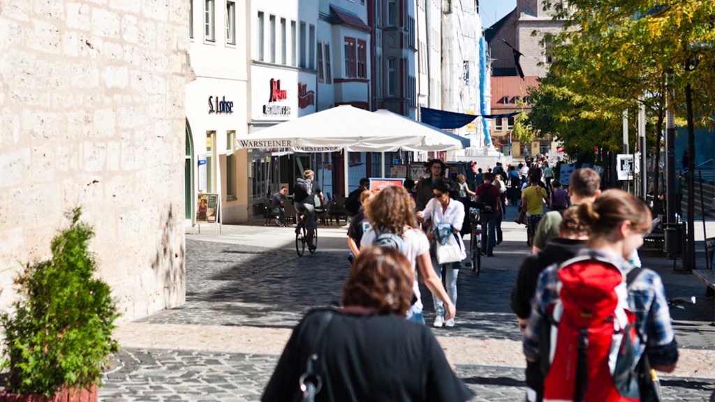 Menschen laufen durch eine Fußgängerzone in der Innenstadt von Jena