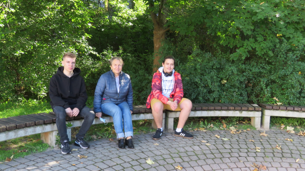 Jovan Schwabe, Monika Klaus und Jonas Hielscher sitzen auf einer Bank im Außengelände des LISA Lobeda