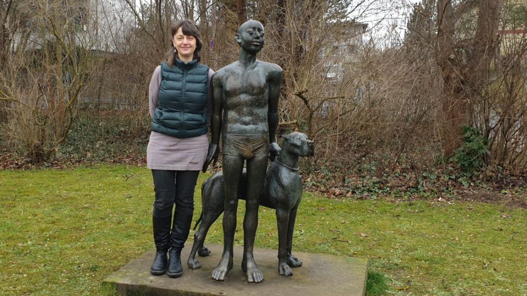 Kathrin Jaekel neben einer Skulptur im Garten des Stadtteilzentrums LISA
