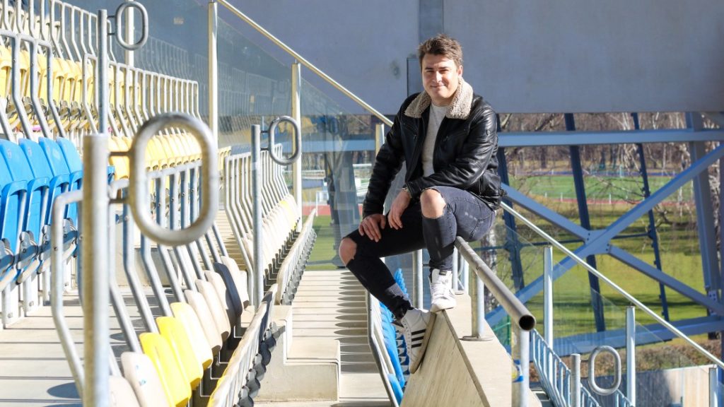 Felix Reichenbacher auf einem Geländer im Stadion des FC Carl-Zeiss Jena sitzend