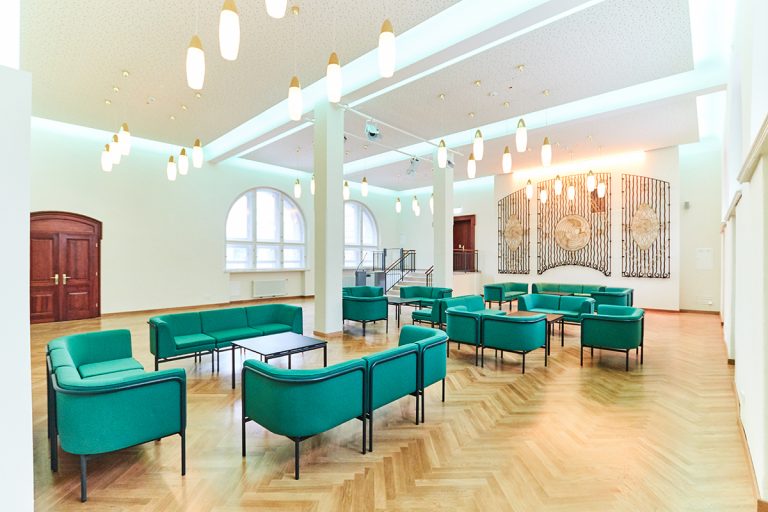 Volkshaus Jena, im Hermann-Schaeffer-Saal, grüne Loungemöbel und viele goldene Lampen, ein denkmal an der Wand