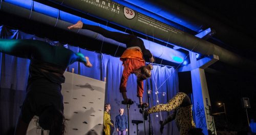 Akrobatinnen machen einen Handstand unter der Fernwärmetrasse "CircusRomantik"
