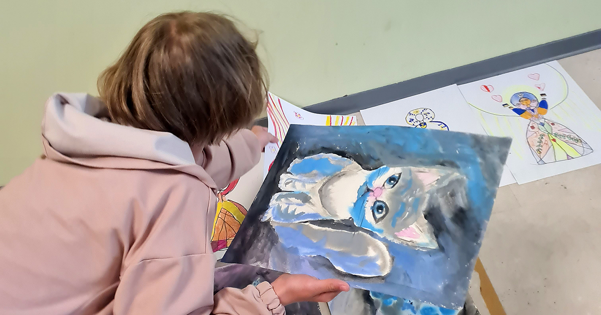 Ein Kind mit selbst gemalten Bildern
