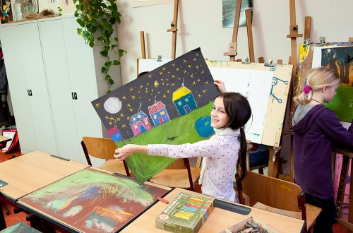 Ein kleines Mädchen hält stolz ihr fertiges Gemälde hoch