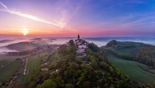 Die Leuchtenburg im Abendrot, etwas Nebel zieht durch das Tal, die Burg thront auf einem Hügel