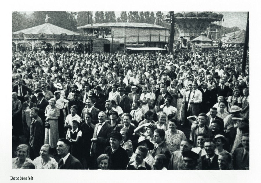 Historische Postkarte "Paradiesfest" von 1936, auf der viele Menschen im Grünen mit Karussels im Hintergrund abgebildet sind