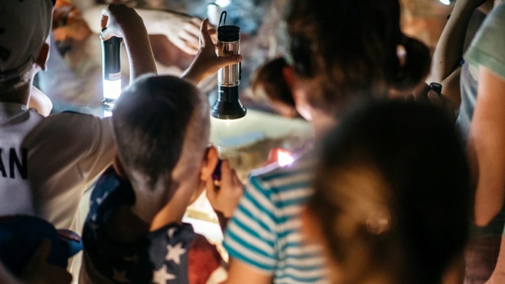 Kinder mit Taschenlampen an einer Vitrine in den Städtischen Museen Jena