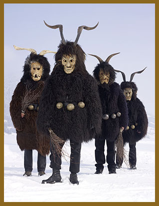 Fotografie von Charles Fréger aus der Serie "Wilder Mann": Vier Menschen in einer Schneelandschaft in dicken dunklen Pelzen, die mit großen Schellen behangen sind. Sie tragen archaische Masken mit gedrehten Hörnern.