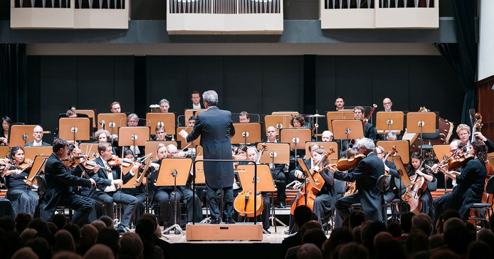 Blick vom Zuschauerraum auf die Bühne mit der Jenaer Philharmonie und GMD Simon Gaudenz im Volkshaus Jena
