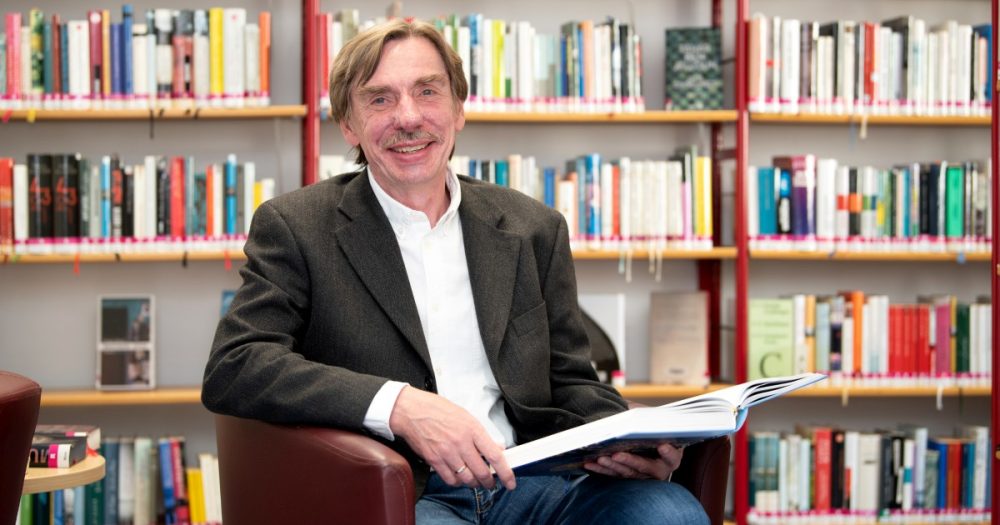 Stadthistoriker Rüdiger Stutz sitzt in einem Sessel und blättert im Jenaer Stadtlexikon