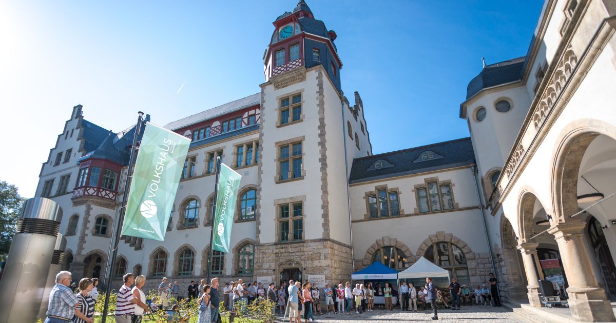 Oberbürgermeister hält eine Rede auf dem Vorplatz mit Pavillons und Besucher:innen beim Tag der offenen Tür im Volkshaus Jena