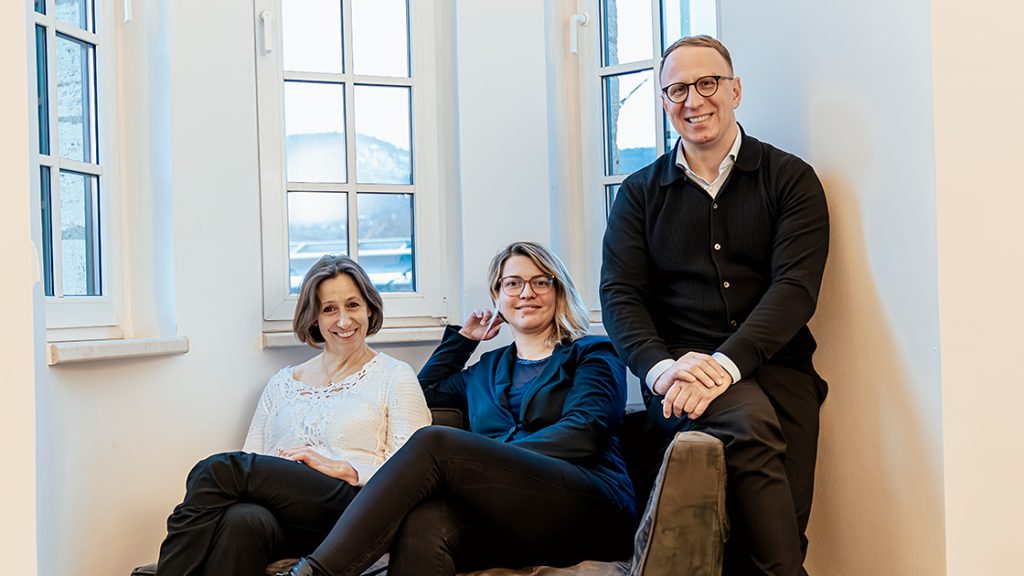 JenaKultur-Werkleitung mit Friedrun Vollmer, Carsten Müller, Jana Gründig, sitzen auf einer kleinen Couch vor einem Fenster