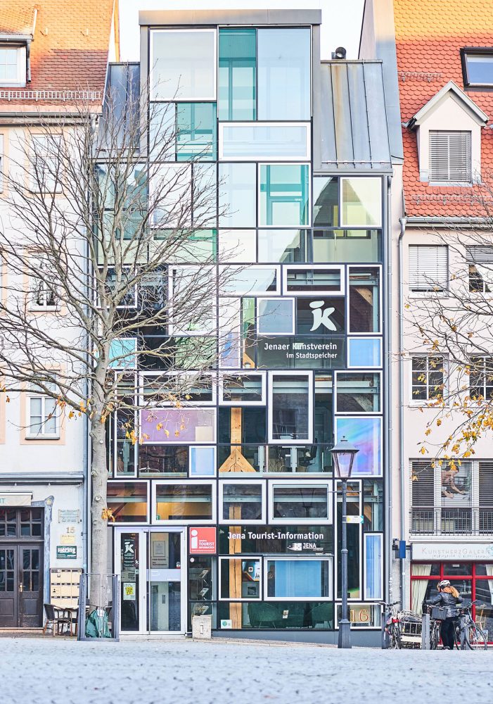 Frontansicht eines mit einzelnen Glasscheiben verglasten Gebäudes, in dem sich die Tourist-Information Jena befindet