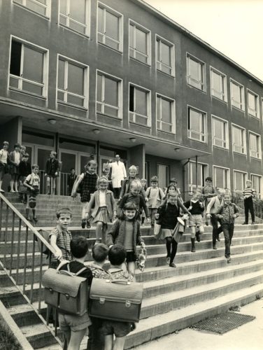 Historisches Foto aus der DDR von Schulkindern, die ein Schulgebäude verlassen