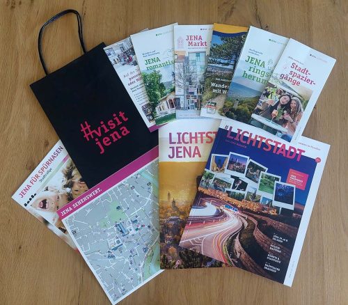 Verschiedene Broschüren, Magazine, Flyer, ein Stadtplan und eine Papiertüte mit Aufdruck #visitjena des Tourismusmarketing Jena