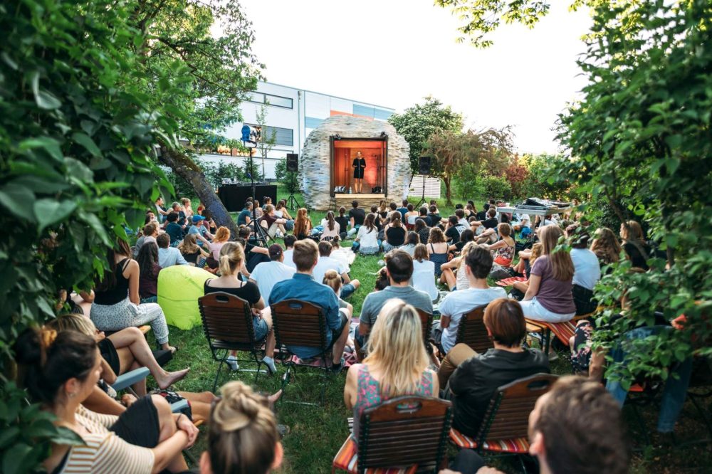 Das Gartenkunst-Objekt Folly der Villa Rosenthal wurde zu einer Bühne umfunktioniert und präsentiert Poetry Slam für das auf der Wiese sitzende Publikum.