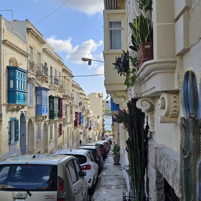 Eine Straße zum Meer in Malta, die Häuser haben die typischen bunten Balkone