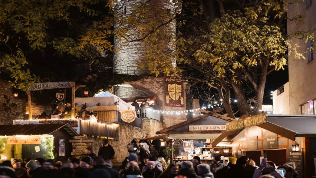 Historischer Weihnachtsmarkt zu Jena mit mittelalterlichen Ständen, Menschen und einer Stadtmauer