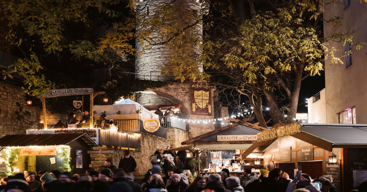 Historischer Weihnachtsmarkt zu Jena mit mittelalterlichen Ständen, Menschen und einer Stadtmauer