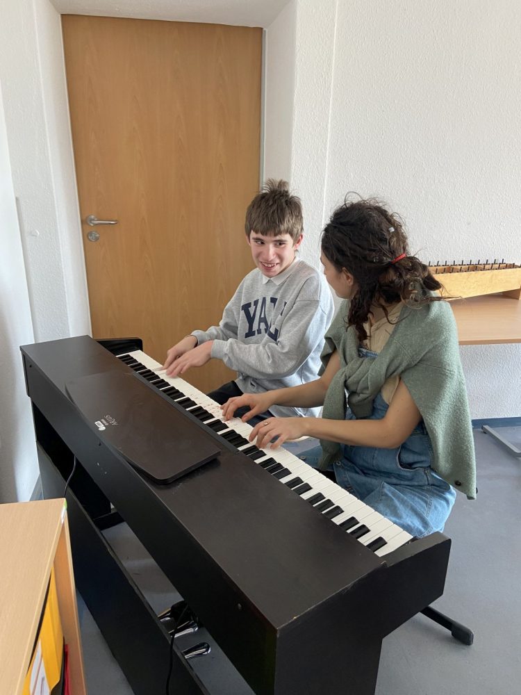 Ein Junge spielt gemeinsam mit einer Musikschullehrerin Klavier.