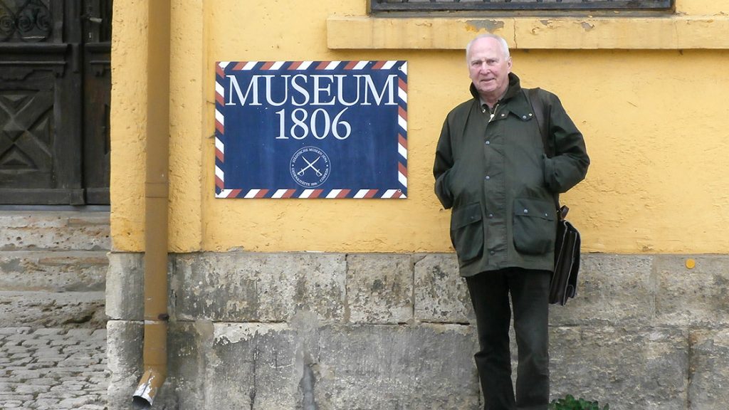 Günther Queisser steht draußen vor einem Schild mit der Aufschrift "Museum 1806"