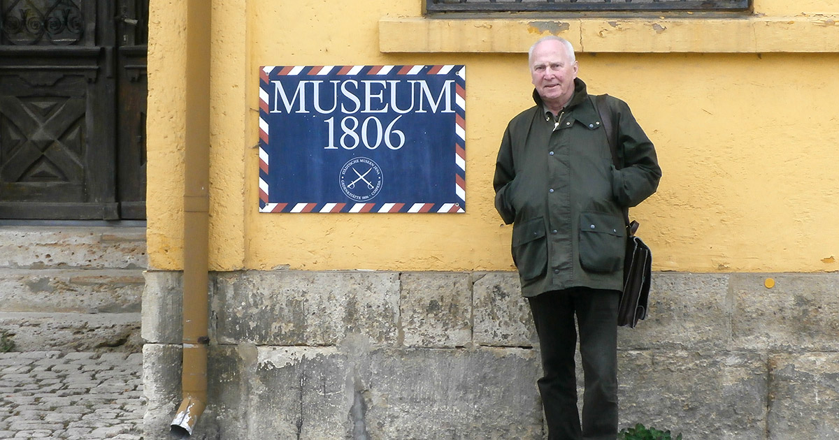 Günther Queisser steht draußen vor einem Schild mit der Aufschrift "Museum 1806"