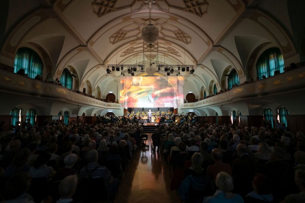 Blick auf die Bühne im Volkshaus Jena mit Orchester und Lichtkunst im Hintergrund