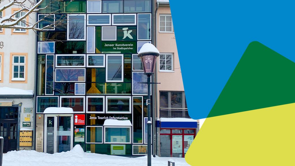 Blick auf die verschneite Jena Tourist-Information mit JenaKultur-CD-Würfeln am rechten Rand