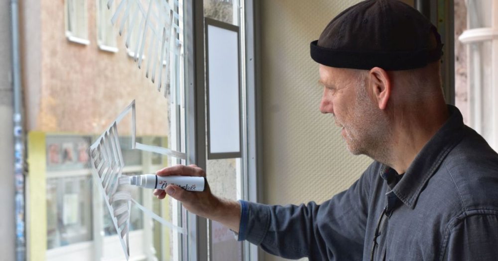 Ekkehard C. Engelmann mal mit weißer Fensterkreide einen Pfeil an ein Fenster