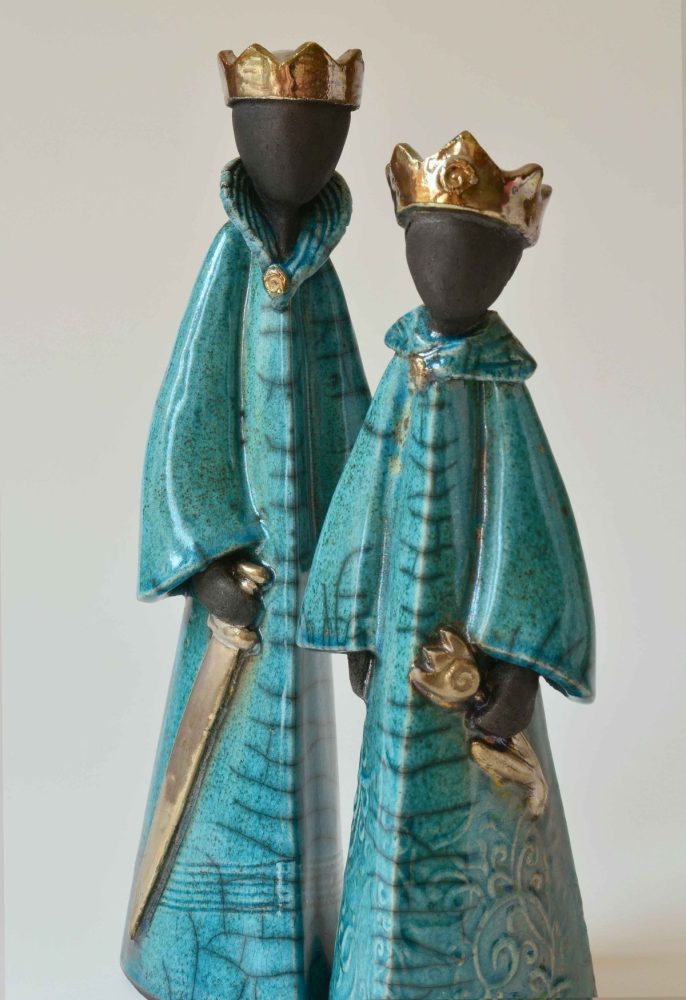 ein Königpaar mit goldenen Kronen und blauen Gewändern. Der König hält ein Schwert, die Königin Figur