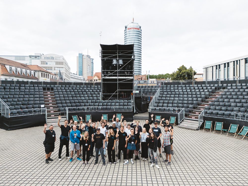 Gruppenbild Kulturarena-Team auf dem Theatervorplatz in Jena, ca. 20 Personen, links steht Martin Hädrich und winkt