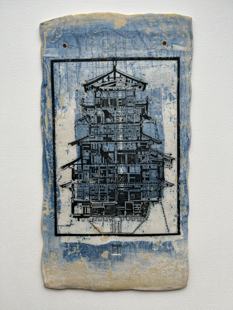 Das Bild zeigt einen Japanischen Turm mit mehreren Etagen. Der Turm ist schwarz gehalten, während der Hintergrund blau und beige ist.