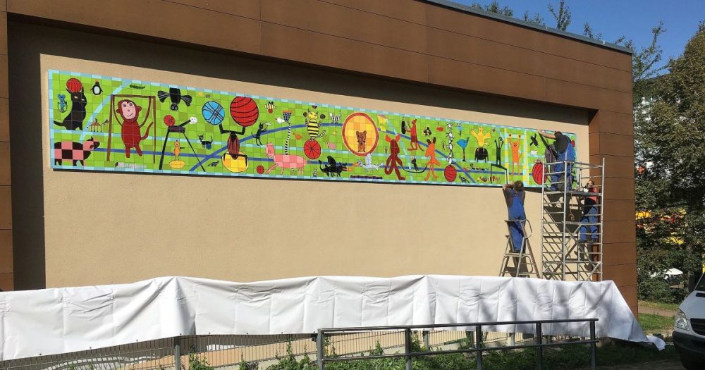 ein langes, schmales buntes Bild an einer Hauswand. Das Bild enthält viele verschiedene kleine Motive. Tiere machen Sport