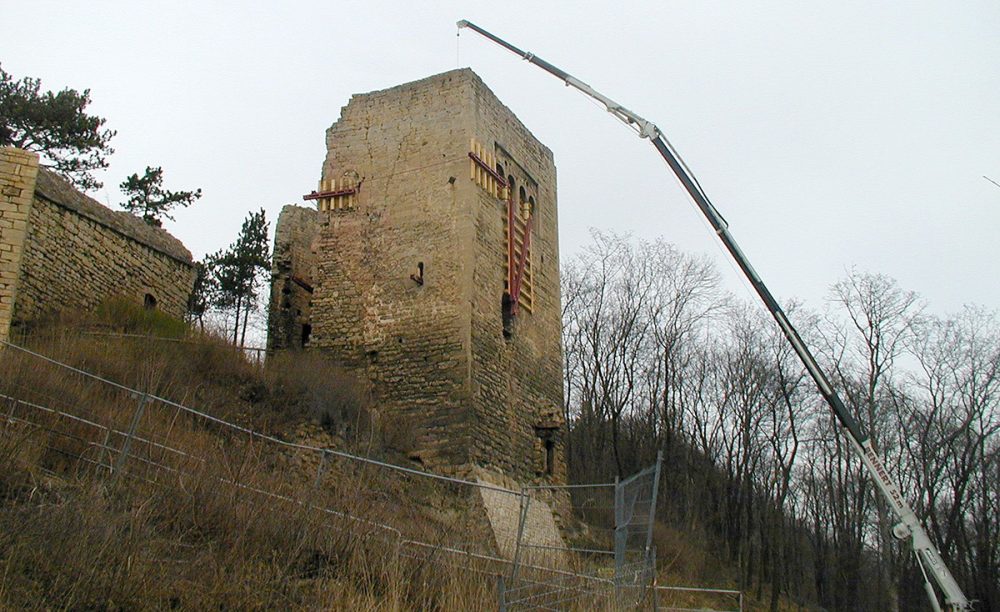 Notsicherung der Lobdeburg mit Stahltraversen, ein Kran steht vor einem Turm der Ruide, Traversen sichern den Turm von außen