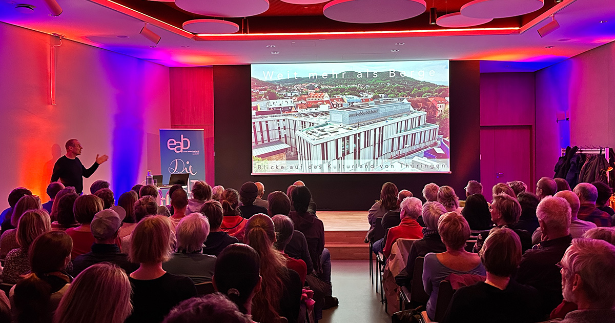 Blick auf eine Bühne mit einer Präsentation und Publikum