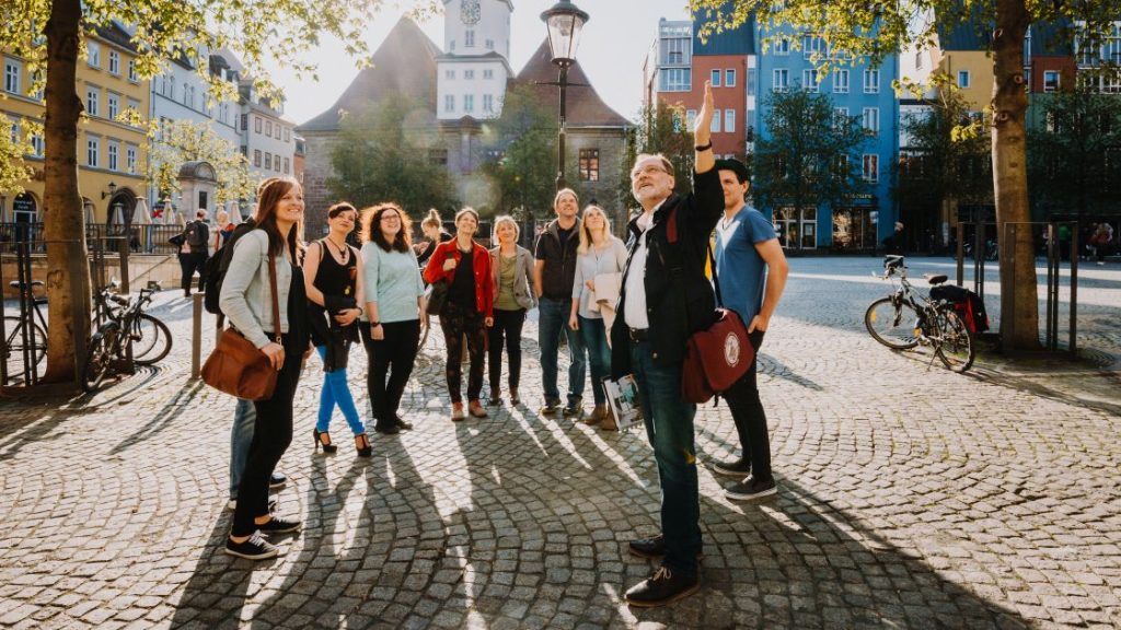 Teilnehemende einer Stadtführung stehen auf dem Marktplatz Jena