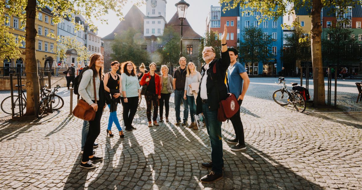 Teilnehemende einer Stadtführung stehen auf dem Marktplatz Jena