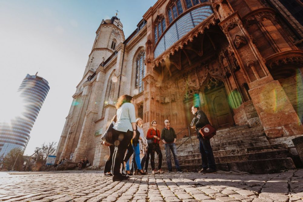 Eine Gruppe mit Teilnhemer:innen der Stadtführung steht vor der Stadtkriche St. Michael