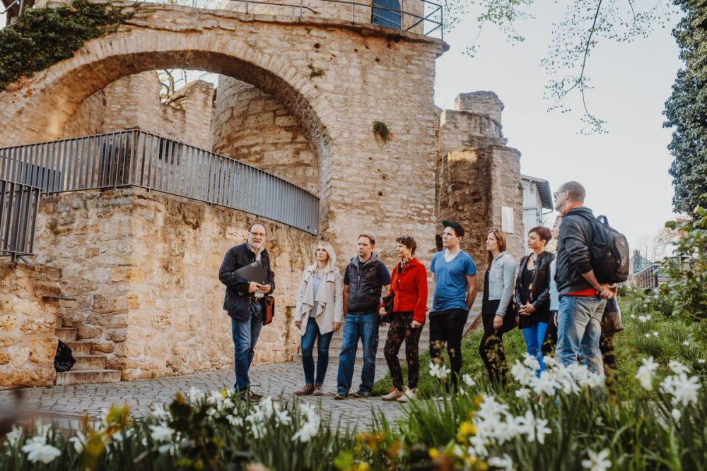 Gruppe von Teilnehmer:innen der Stadtführung an der historischen Stadtmauer