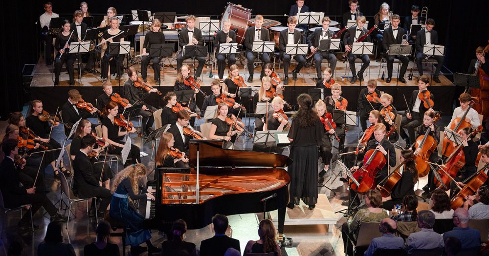 Bühne mit einem Orchester und Elsa-Johanna Staemmler am Flügel