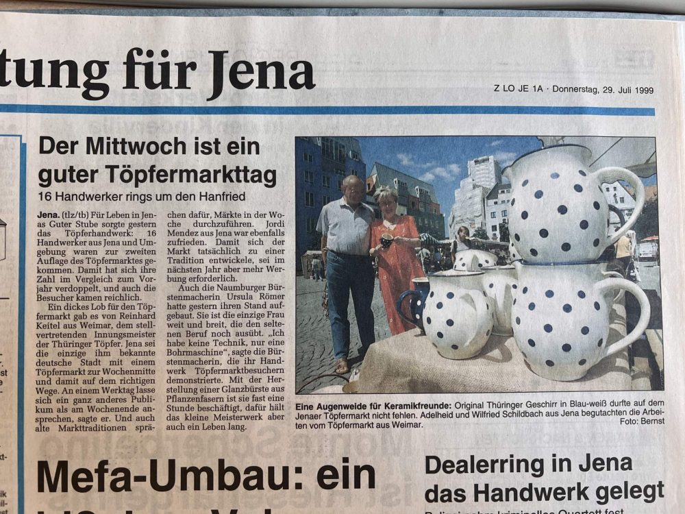 Zeitungsausschnitt von 1999 über den Jenaer Töpfermarkt mit Foto von Menschen vor einem Stand mit blau-weiß gepunktetem Keramikgeschirr.