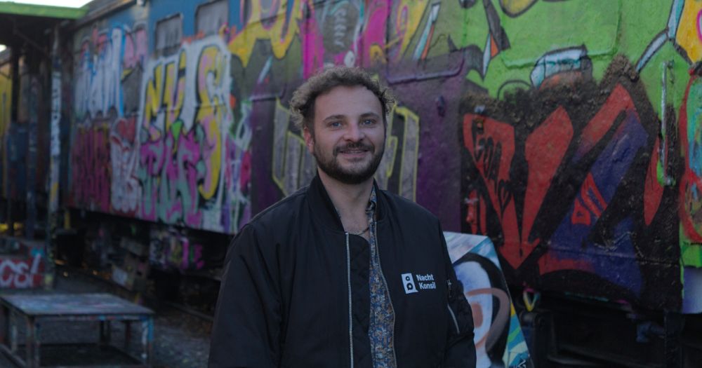 Junger Mann vor einer Wand voller Graffitti