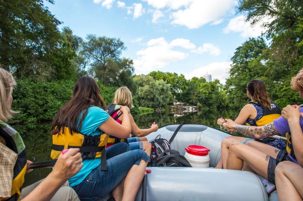 Menschen sitzen auf einem Schlauchboot und fahren auf der Saale