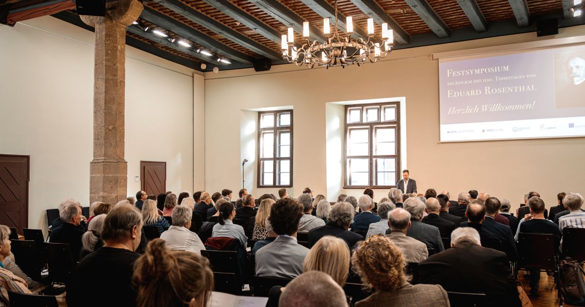 Mann im Anzug spricht am Rednerpult, vor ihm sitzendes Publikum im Saal.