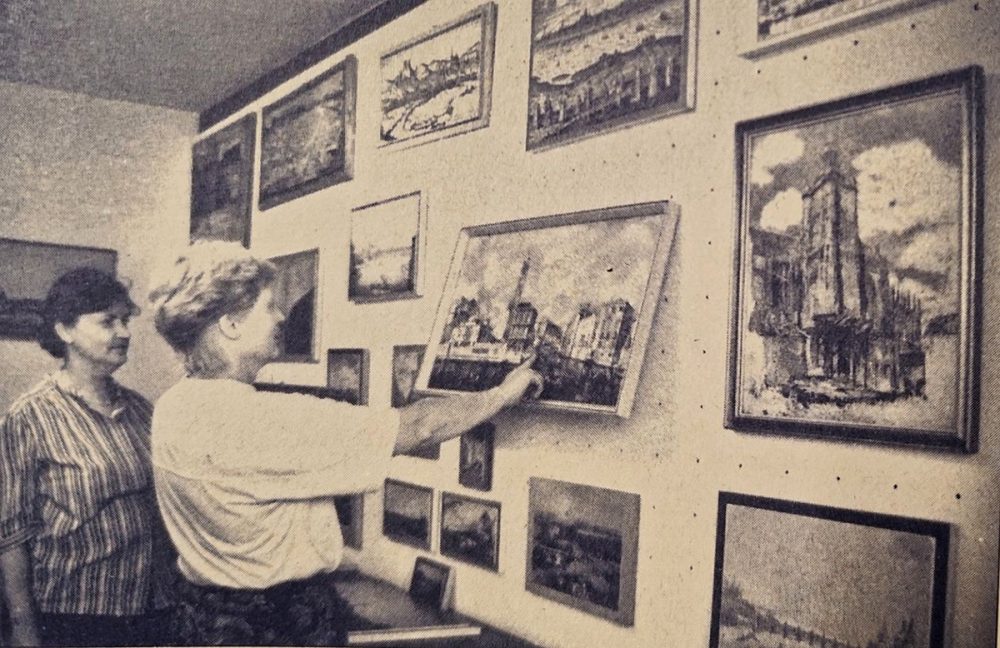 zwei Frauen schauen sich Bilder an die an einer Wand hängen