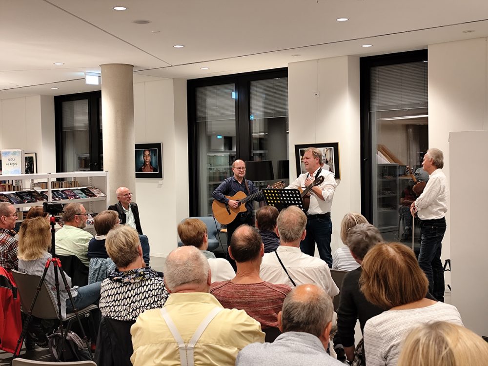 Zwei Männer mit Gitarren auf einer Bühne und Publikum