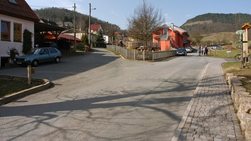 Eine öffentliche Straße, die sich in zwei kleinere Straßen gabelt. In der Mitte steht ein rotes Haus.